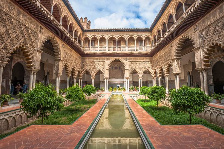 A view of the Alcázar of Seville with intricate Mudejar architecture and lush gardens Alcazar Sevilla 2026. A stunning view of the Alcázar of Seville, showcasing its intricate Mudejar architecture and lush gardens with a blend of Islamic and Christian influences Alcazar Sevilla 2026.